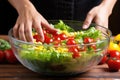 hand tossing lettuce, tomatoes and corn in a salad bowl