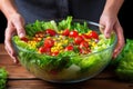 hand tossing lettuce, tomatoes and corn in a salad bowl