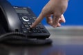 Hand touch number for calling to custommer,Closeup ip phone black color on the wood floor Royalty Free Stock Photo