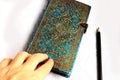 Hand touching closed diary notebook with red ribbon bookmark pencil and lock