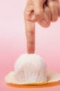 Hand touching delicious strawberry daifuku, Japanese rice cake against pink background Royalty Free Stock Photo