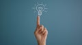 A hand touching a drawn lightbulb symbolizing an idea on a teal background.. AI generated Royalty Free Stock Photo