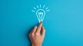 A hand touching a drawn lightbulb symbolizing an idea on a teal background.. AI generated Royalty Free Stock Photo