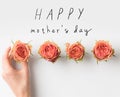 hand touching pink rose buds placed in row with HAPPY MOTHERS DAY inscription Royalty Free Stock Photo