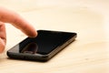 Hand touching screen of black smartphone