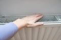 A hand touching white radiator of a central heating system, checking the temperature of a heater, warm and cozy home Royalty Free Stock Photo