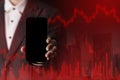 Hand of a trader holding a smartphone And the red bar chart shows investment losses, investment risks, stock market downturns