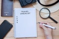 Hand traveler writing Travel Checklist word on notebook with accessories, Camera, Passport, Magnifying, smart Phone and hat on Royalty Free Stock Photo