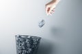 Hand trowing a paper into a wastebasket on gray background Royalty Free Stock Photo