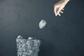 Hand trowing a paper into a wastebasket on gray concrete wall background Royalty Free Stock Photo