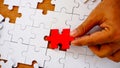 Hand try to put and lay the red color jigsaw on white color jigsaw empty area Royalty Free Stock Photo