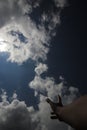 Hand trying to reach Stratocumulus clouds with a clear blue sky background in the midday. Royalty Free Stock Photo