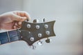 Hand tuning a guitar from headstock.hand guitarist adjusting pegs on acoustic guitar during music lesson at home Royalty Free Stock Photo