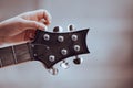 Hand tuning a guitar from headstock.hand guitarist adjusting pegs on acoustic guitar during music lesson at home Royalty Free Stock Photo