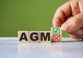 The hand turn wooden block with red reject X and green confirm tick as change concept of AGM. Word AGM conceptual symbol Royalty Free Stock Photo