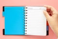 Hand turning blank page of notebook on pink background Royalty Free Stock Photo