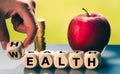 Hand is turning a dice and changes the word `health` to `wealth`.
