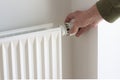 Hand turning down adjusting knob on thermostat on radiator valve to save energy Royalty Free Stock Photo
