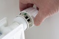 Hand turning down adjusting knob on thermostat on radiator valve to save energy Royalty Free Stock Photo