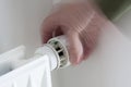 Hand turning down adjusting knob on thermostat on radiator valve to save energy Royalty Free Stock Photo