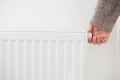 Hand turning down thermostat of a central heating radiator. Royalty Free Stock Photo