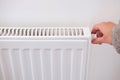 Hand turning down thermostat of a central heating radiator. Royalty Free Stock Photo