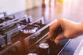 Hand turning on gas burner on kitchen stove top Royalty Free Stock Photo
