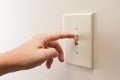 Hand turning wall light switch off.