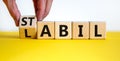 Hand turns a cube and changes the German word `labil` - unstable in English to `stabil` - stable in English. Beautiful yellow