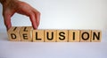 Hand turns a cube and changes the word delusion to illusion. Beautiful white background. Business concept. Copy space