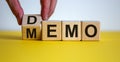 Hand turns a cube and changes the word `DEMO` to `MEMO` on wooden cubes. Beautiful yellow table, white background, copy space