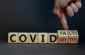 Hand turns cubes and changes the expression `covid myths` to `covid facts`. Beautiful grey background. COVID-19 pandemic conce