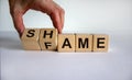 Hand turns cubes and changes the word shame to fame. Beautiful white background. Business concept. Copy space