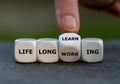 Hand turns dice and changes the expression `life long working` to ` life long learning`. Royalty Free Stock Photo