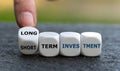 Hand turns dice and changes the expression `short term investment` to `long term investment` Royalty Free Stock Photo