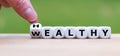 Hand turns a dice and changes the expression `healthy` to `wealthy`. Royalty Free Stock Photo