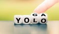 Hand turns dice and changes the expression `yolo` to `yoga`, or vice versa.