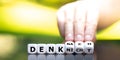 Hand turns dice and changes the German expression `denk nicht` do not think to `denk nach` think.