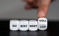 Hand turns dice and changes the German expression `du bist wertlos` you are worthless to `du bist wertvoll`you are valuable Royalty Free Stock Photo