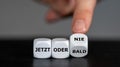Hand turns dice and changes the German expression `jetzt oder bald` now or soon to `jetzt oder nie` now or never.