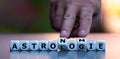 Hand turns dice and changes the German word `Astrologie` `Astrology` to `Astronomie` `Astronomy`.