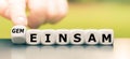 Hand turns a dice and changes the German word `einsam` `lonely` in English to `gemeinsam` `together` in English.