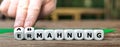 Hand turns dice and changes the German word 'Ermahnung' to 'Abmahnung' . Royalty Free Stock Photo