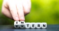 Hand turns dice and changes the German word `extern` external to `intern` internal.