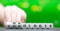 Hand turns dice and changes the German word `Ideologie` ideology to `Ãâkologie` ecology. Royalty Free Stock Photo