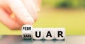 Hand turns a dice and changes the German word `Januar` `January` in English to `Februar` `February` in English.