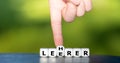 Hand turns dice and changes the German word `Leerer` empty to `Lehrer` teacher.