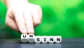 Hand turns dice and changes the German word `Sinn` sense to `unsinn` nonsense.