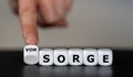 Hand turns dice and changes the German word `Sorge` concern to `Vorsorge` precaution.