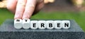 Hand turns dice and changes the German word 'Sterben' (die) to 'erben' (inherit).